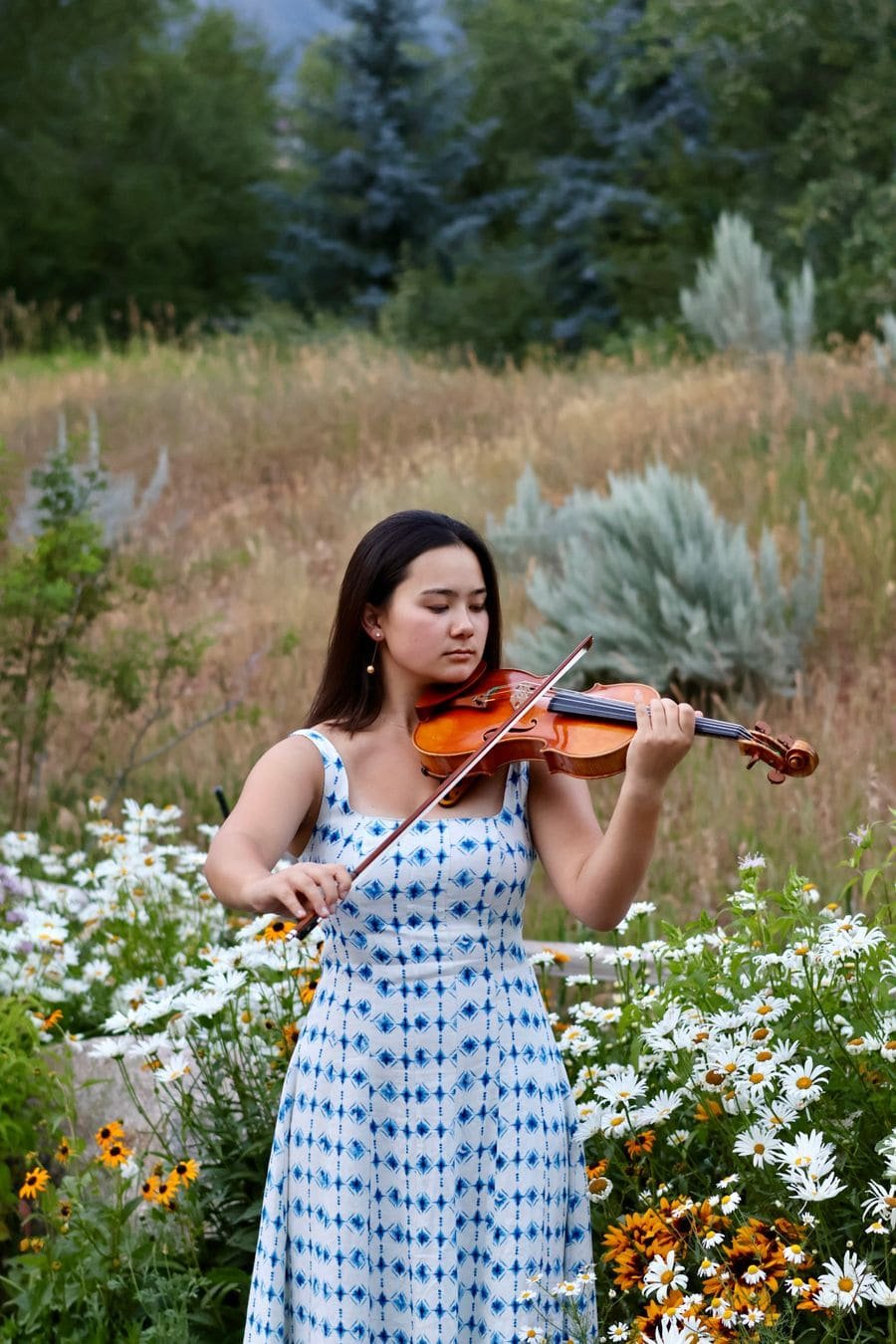 Mari Roes playing violin in a Colorado wildflower meadow